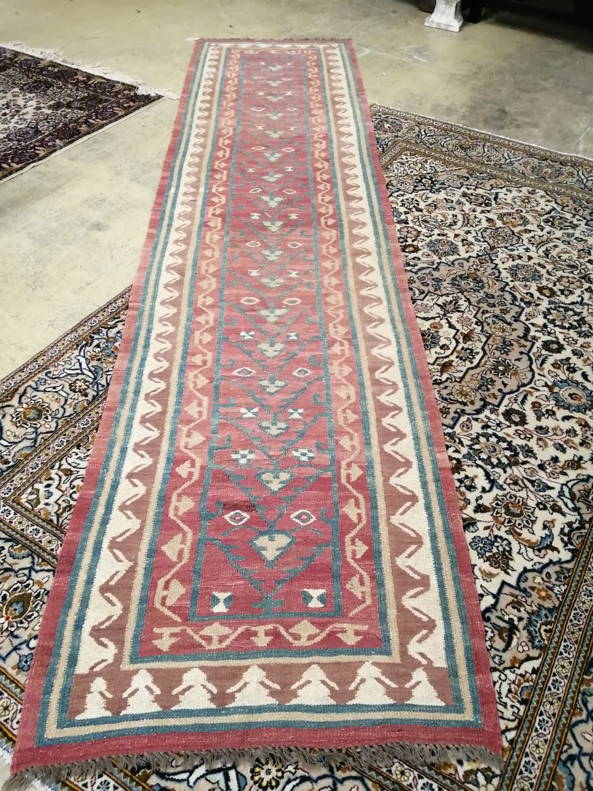 A Kilim runner with geometric motifs on a red ground, 394 x 96cm